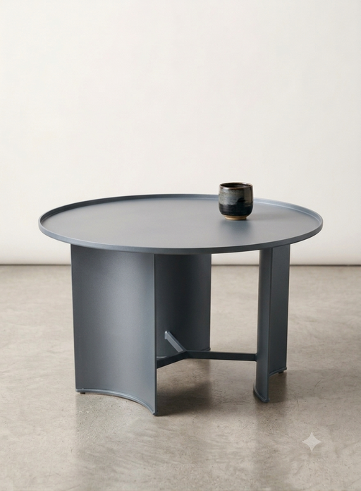 Bring a bold splash of contemporary geometry and industrial minimalism to your living room with The Orbit Coffee Table. Crafted entirely from high-grade sheet metal, this sleek accent piece stands out with its architectural design, featuring three broad, elegantly curved panel legs anchored by a clean industrial center brace.
The tabletop is designed with a subtle tray-like raised edge, giving it a distinct modern profile while keeping items securely in place. Finished in an ultra-smooth, matte powder coating, this table effortlessly resists scratches and is incredibly easy to wipe clean. Available in three curated earthy tones, it serves as the perfect low-profile centerpiece to tie together a modern, Scandinavian, or urban loft aesthetic.


Architectural Curved Legs: Features unique, wide-radius curved metal panels that provide a beautiful interplay of light and shadow from every angle.


Functional Tray-Top Lip: The clean, raised perimeter edge prevents spills and adds an editorial, industrial-chic frame to your tabletop decor.


Premium Matte Powder-Coated Finish: Engineered for durability, the heavy-duty matte coating offers a velvety, non-reflective surface that protects against daily wear.


3. Dimensions


Diameter: 75 cm


Height: 42 cm


Edge Lip Height: 1.5 cm


4. Material &amp; Color Options


Composition: 100% Premium Grade Carbon Steel (Matte Powder-Coated Finish)


Available Colors:


Slate Blue-Grey


Ochre Mustard Yellow


Forest Green



