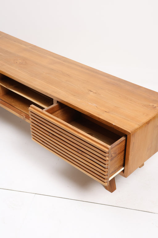 The Lia TV Unit is a statement piece that blends contemporary textures with mid-century soul. Crafted from premium solid wood, this unit features eye-catching slatted drawer fronts that provide a rhythmic, tactile quality to your living space. Designed with a clean, low-profile silhouette and angled tapered legs, it offers the perfect balance of open-air display and hidden storage.


Slatted Detail: Two precision-crafted slatted drawers offer a unique aesthetic while keeping clutter out of sight.

Open Media Hub: A central open shelf with a divider, perfect for consoles, cable boxes, or soundbars.

Handcrafted Quality: Made from durable solid wood with a smooth, natural finish that highlights the timber's unique grain.

Minimalist Frame: Rounded edges and splayed legs create a soft yet structured look.

