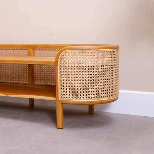 Redefine your living space entertainment layout with the spectacular Levi TV Console. Embodying the core Urban Oak design ethos—where clean, contemporary architectural shapes beautifully intertwine with raw, organic materials—this handcrafted media bench is a triumph of modern organic styling.
By combining a warm, hand-polished wood frame with the curved, breathable texture of genuine woven rattan, it establishes immediate warmth and curated designer luxury in your home. In a furniture market saturated with mass-produced, lightweight particle board and synthetic plastic veneer composites, the Levi commands respect as a premium legacy piece, hand-shaped to perfection.
Why You'll Love It


Iconic Capsule Silhouette: Features a striking, pill-shaped oval design with smoothly rounded sides. This continuous fluid framework softens the harsh corners of standard living spaces, serving as a functional media center that doubles as high-end sculptural art.

Authentic Natural Rattan Accents: Wrapped in premium, hand-woven natural rattan cane panels along its curved outer sides. This breathable, organic webbing injects soft Bohemian texture and a coastal, sun-drenched lightness to your entertainment zone.

Solid Wood Heart &amp; Joinery: Meticulously handcrafted from premium sustainable solid timber to offer absolute structural stability and a heavy-duty, weighted foundation built to safely support large flat-screen TVs.

Naturally Ventilated Media Compartment: Designed with a generous full-length open shelf layout. The open weave of the rattan backing acts as a natural ventilation system, making it the perfect cool, heat-dissipating landing pad for cable boxes, gaming systems, and soundbars.

Product Specifications



Attribute
Details




Material
100% Solid Teak Wood &amp; Natural Woven Rattan Cane


Shape
Capsule Footprint / Freestanding Pill-Shaped Media Board


Style
Mid-Century Modern / Organic Boho / Japandi Minimalist / Coastal Chic


Finish
Hand-Polished Natural Satin Wood Tone


Storage Layout
1 Full-Length Open Component Shelf Layer


Overall Dimensions
141 cm (Length) × 45 cm (Height) × 44 cm (Width/Depth)


Usage
Ideal for Living Rooms, Media Lounges, Bed-End Benches, and Entryway Displays



